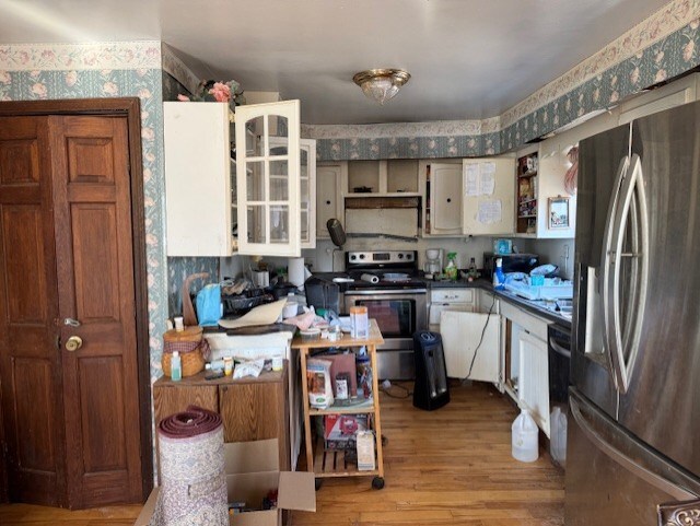 kitchen featuring open shelves, dark countertops, wood finished floors, appliances with stainless steel finishes, and wallpapered walls