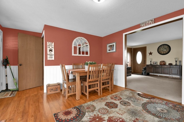 dining area featuring wainscoting, a textured ceiling, and wood finished floors