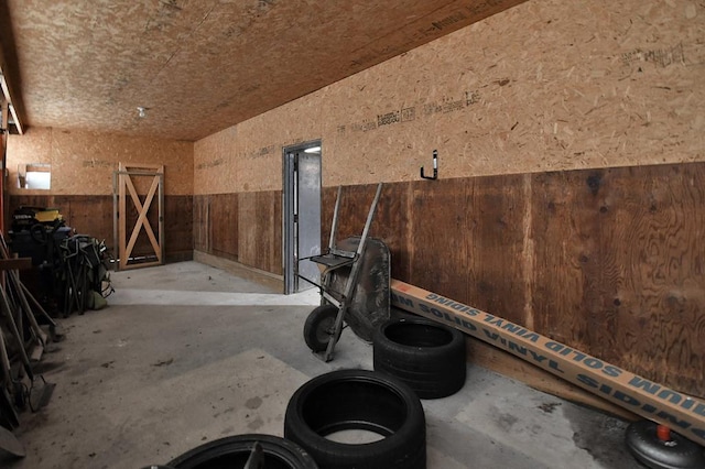 misc room with concrete floors, a wainscoted wall, and vaulted ceiling