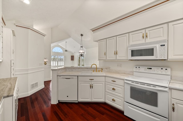 kitchen with a peninsula, white appliances, dark wood-type flooring, white cabinetry, and a sink