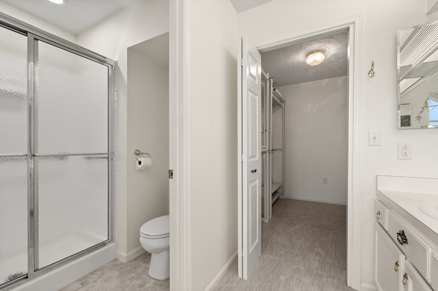 bathroom featuring vanity, baseboards, a shower stall, and toilet