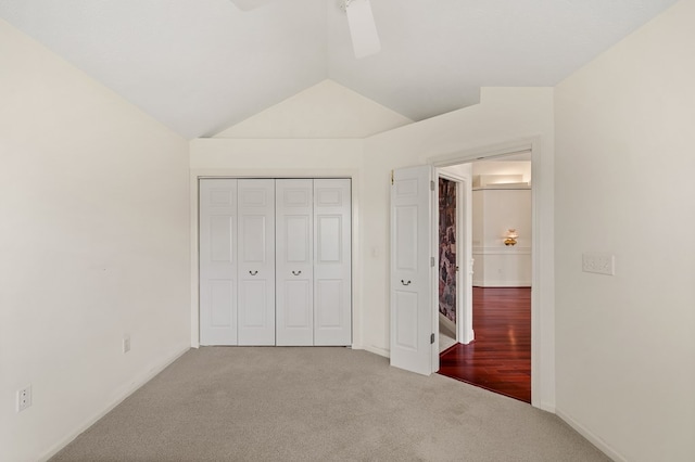 unfurnished bedroom featuring baseboards, lofted ceiling, carpet, and a closet