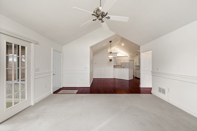 unfurnished living room with ceiling fan, visible vents, baseboards, dark colored carpet, and lofted ceiling