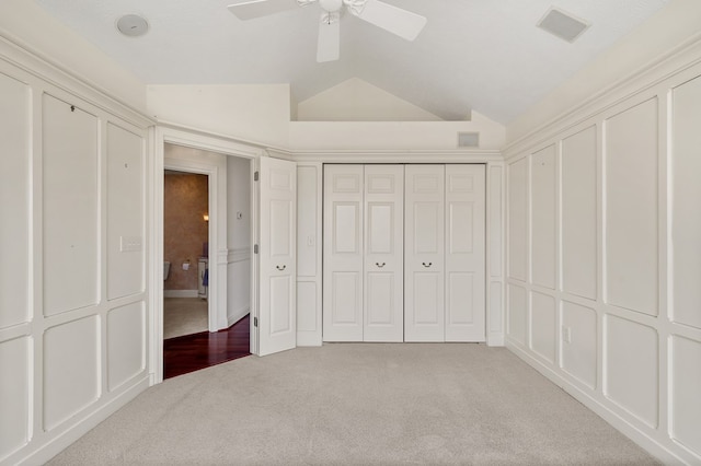 unfurnished bedroom featuring ceiling fan, carpet, vaulted ceiling, and visible vents