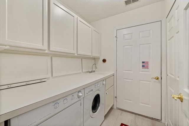 clothes washing area with visible vents, a textured ceiling, a sink, cabinet space, and independent washer and dryer