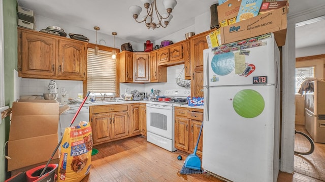 kitchen with light countertops, light wood finished floors, white appliances, a sink, and backsplash