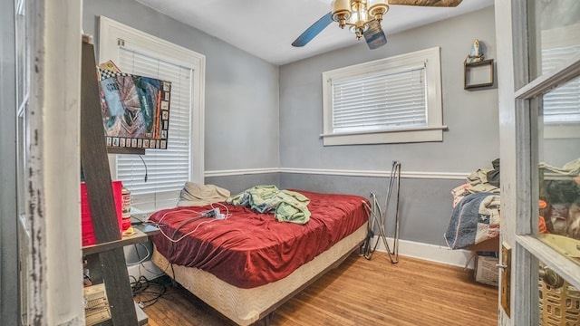 bedroom featuring baseboards, wood finished floors, and a ceiling fan