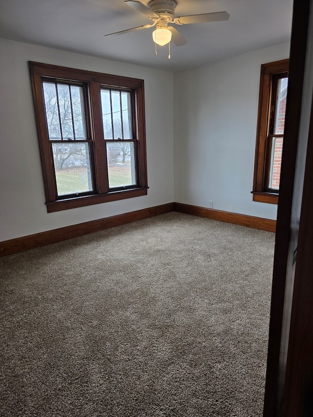 empty room with carpet floors, a ceiling fan, and baseboards