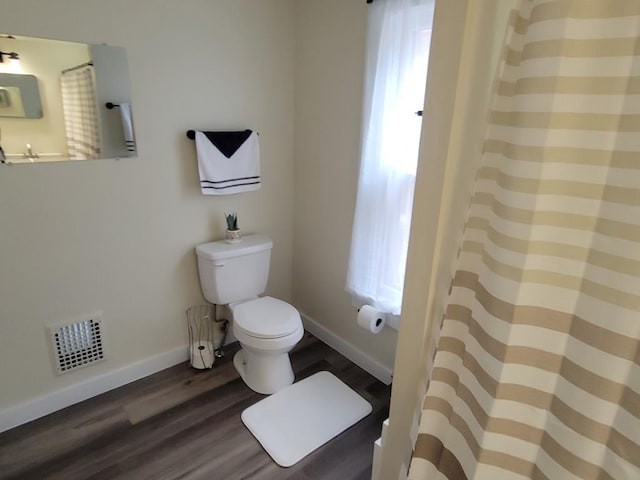 full bathroom with toilet, plenty of natural light, wood finished floors, and visible vents