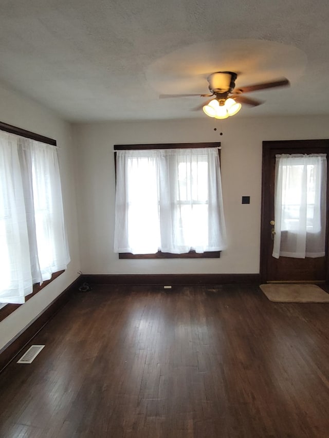 foyer entrance featuring dark wood-style floors, a textured ceiling, visible vents, and baseboards