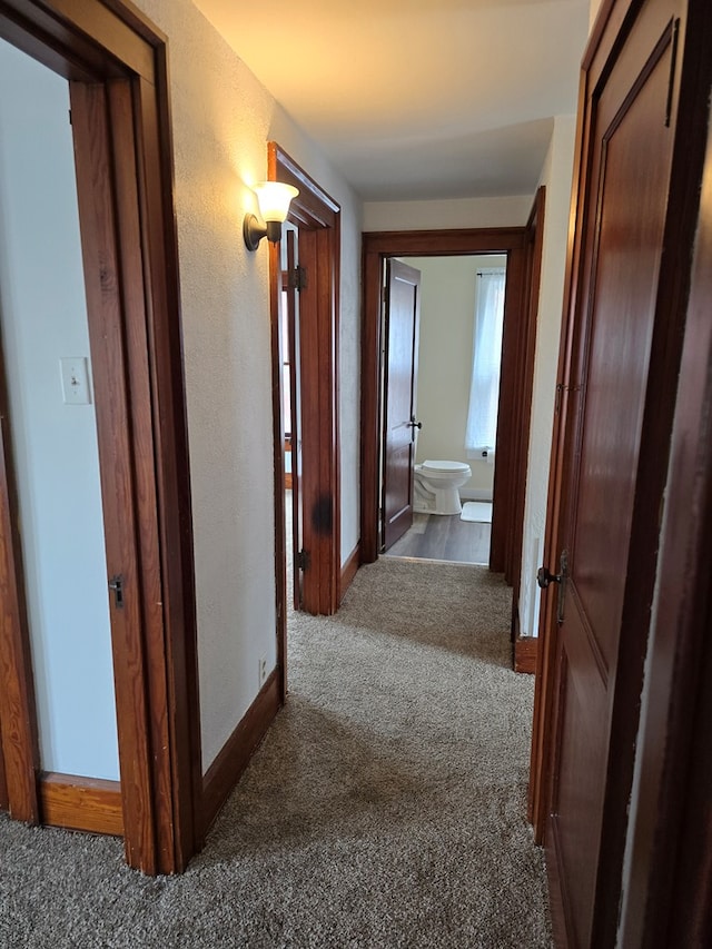corridor with dark carpet and baseboards