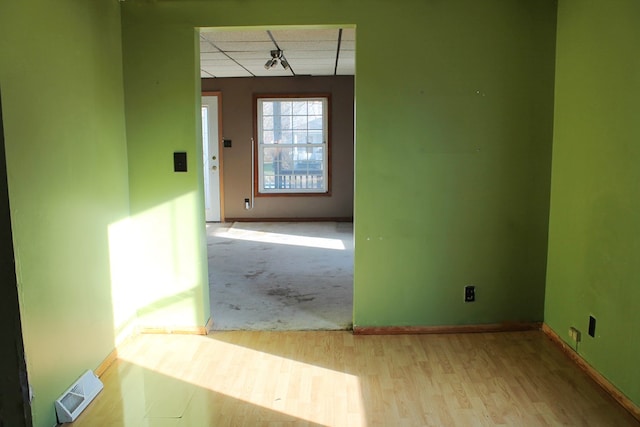 empty room featuring a drop ceiling and light hardwood / wood-style floors