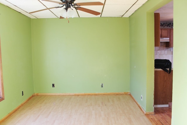 empty room with a paneled ceiling, ceiling fan, and light wood-type flooring