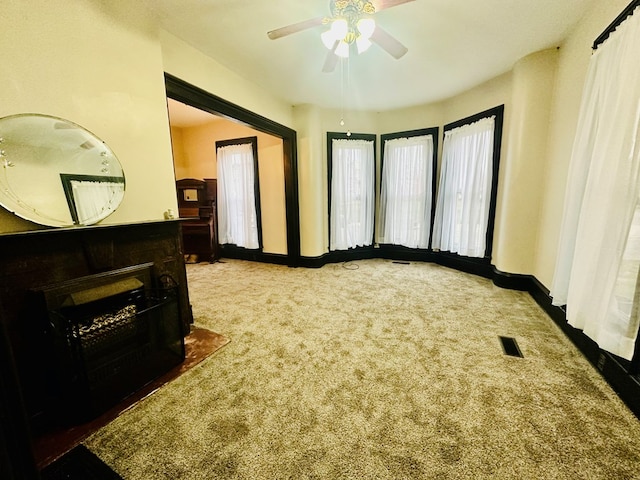 interior space featuring ceiling fan and dark carpet