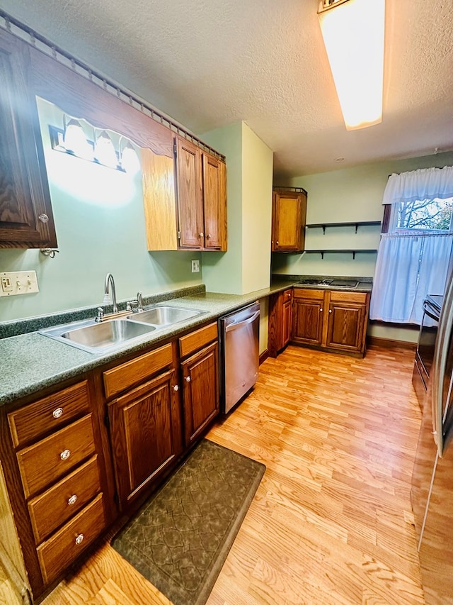 kitchen featuring stainless steel dishwasher, light hardwood / wood-style floors, sink, and a textured ceiling