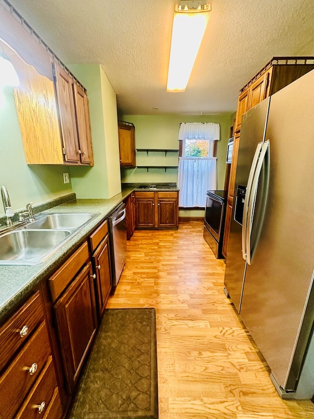 kitchen featuring a textured ceiling, sink, appliances with stainless steel finishes, and light hardwood / wood-style flooring