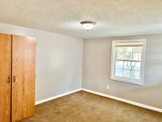 unfurnished bedroom featuring a closet, a textured ceiling, baseboards, and carpet