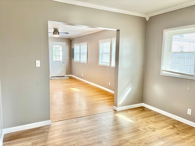 spare room featuring crown molding, baseboards, light wood finished floors, and ceiling fan