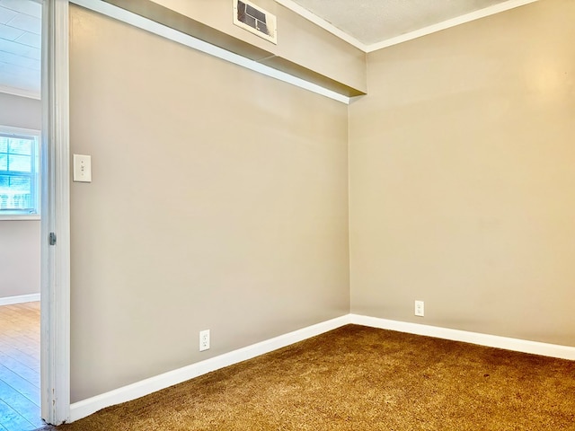 carpeted spare room with visible vents, baseboards, and ornamental molding