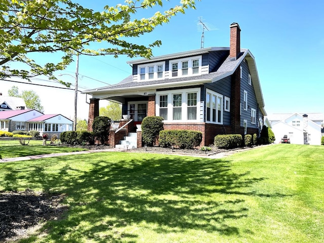 bungalow-style home with a chimney, a front yard, and brick siding