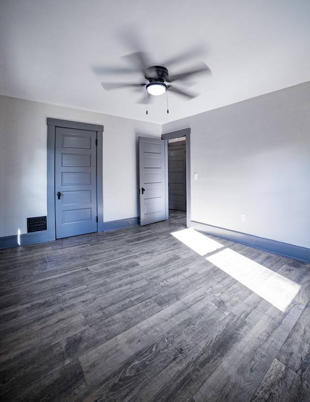 unfurnished bedroom with ceiling fan and dark wood-type flooring