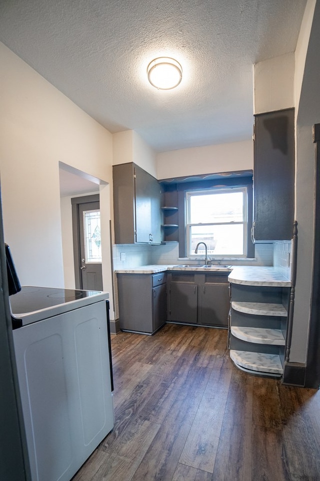 kitchen with gray cabinetry, a textured ceiling, sink, range, and dark hardwood / wood-style floors