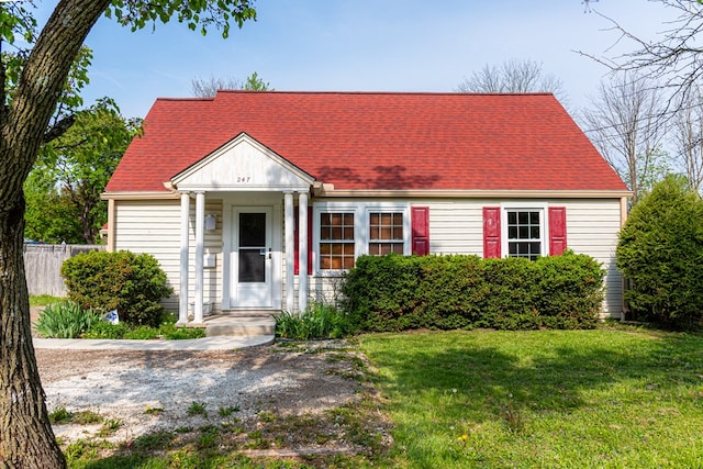 cape cod house with fence, a shingled roof, and a front yard