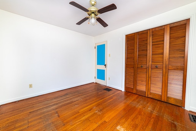 unfurnished bedroom with a ceiling fan, baseboards, visible vents, hardwood / wood-style flooring, and a closet