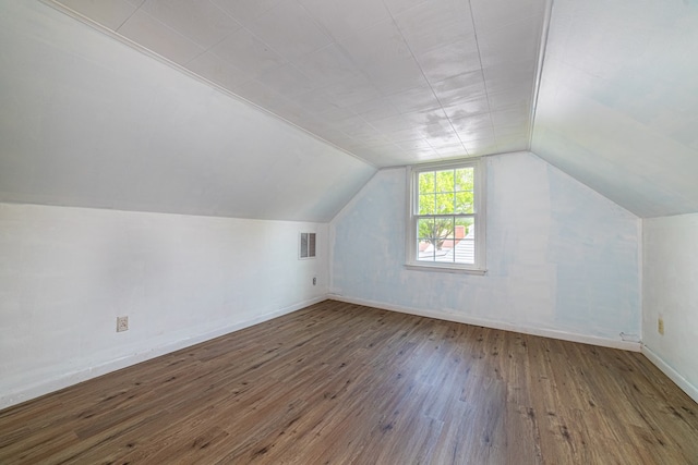 additional living space featuring baseboards, visible vents, hardwood / wood-style floors, and lofted ceiling