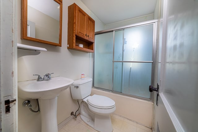 bathroom featuring toilet, a sink, and bath / shower combo with glass door