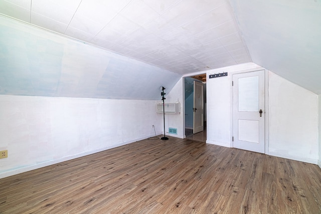 additional living space featuring visible vents, baseboards, wood finished floors, and vaulted ceiling