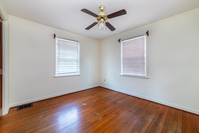 unfurnished room with baseboards, a ceiling fan, hardwood / wood-style floors, and visible vents