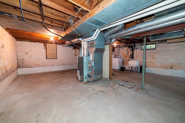 unfinished basement featuring heating unit, visible vents, washer / clothes dryer, and a sink