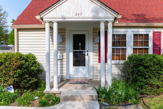 property entrance featuring a shingled roof and a porch
