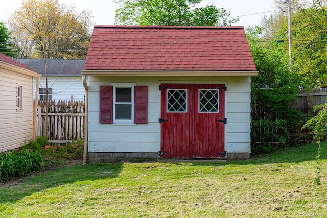 view of outbuilding featuring fence and an outbuilding