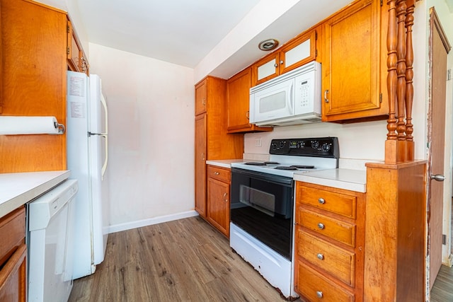 kitchen featuring white appliances, baseboards, light countertops, brown cabinets, and light wood finished floors