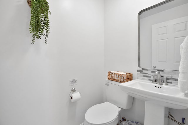 bathroom with backsplash, sink, and toilet