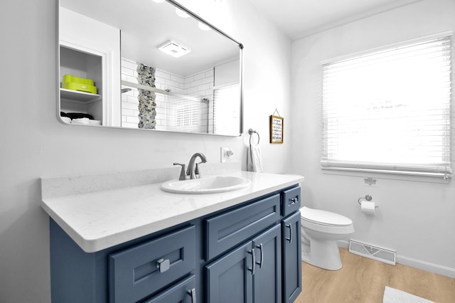 bathroom featuring wood-type flooring, toilet, a shower with shower door, and vanity