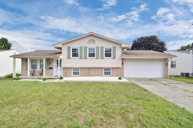 tri-level home featuring a garage, central air condition unit, covered porch, and a front lawn