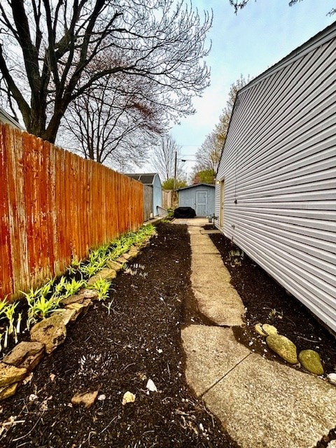 view of yard with fence, an outbuilding, and a shed