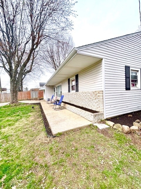 rear view of house featuring brick siding, a patio area, and fence