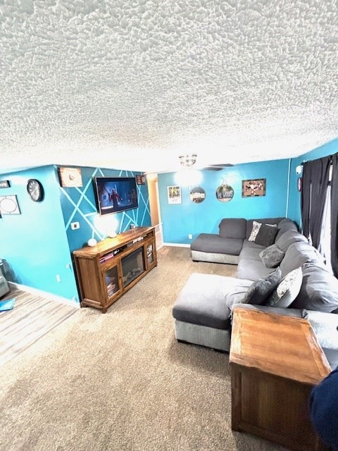 living room featuring baseboards, carpet, and a textured ceiling