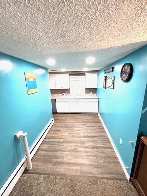 interior space featuring white cabinets, baseboards, a textured ceiling, and light countertops
