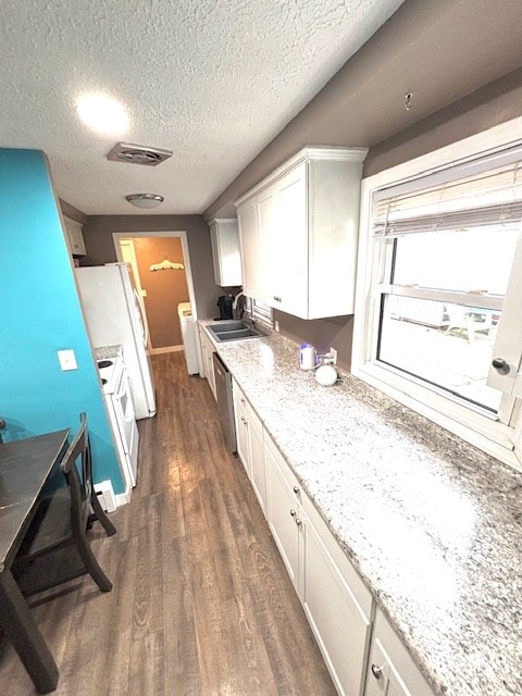 kitchen with white cabinets, dark wood-style floors, visible vents, a sink, and washer / clothes dryer