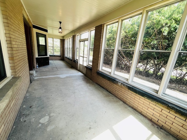 unfurnished sunroom with concrete floors and brick wall