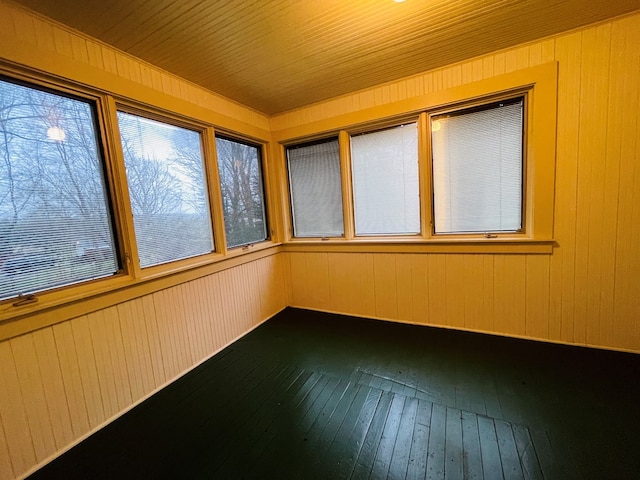unfurnished sunroom featuring hardwood / wood-style floors and wood walls