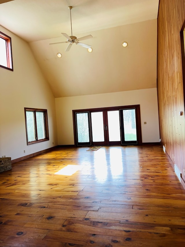 unfurnished living room with high vaulted ceiling, hardwood / wood-style floors, and a healthy amount of sunlight