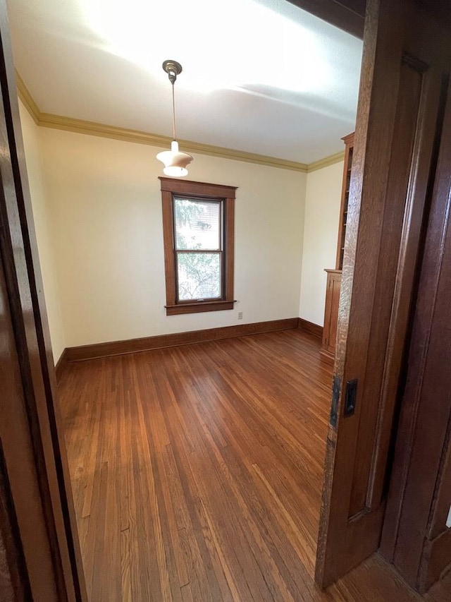 unfurnished room featuring hardwood / wood-style floors, crown molding, and baseboards
