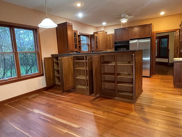 kitchen featuring freestanding refrigerator, open shelves, light wood-style floors, black oven, and baseboards