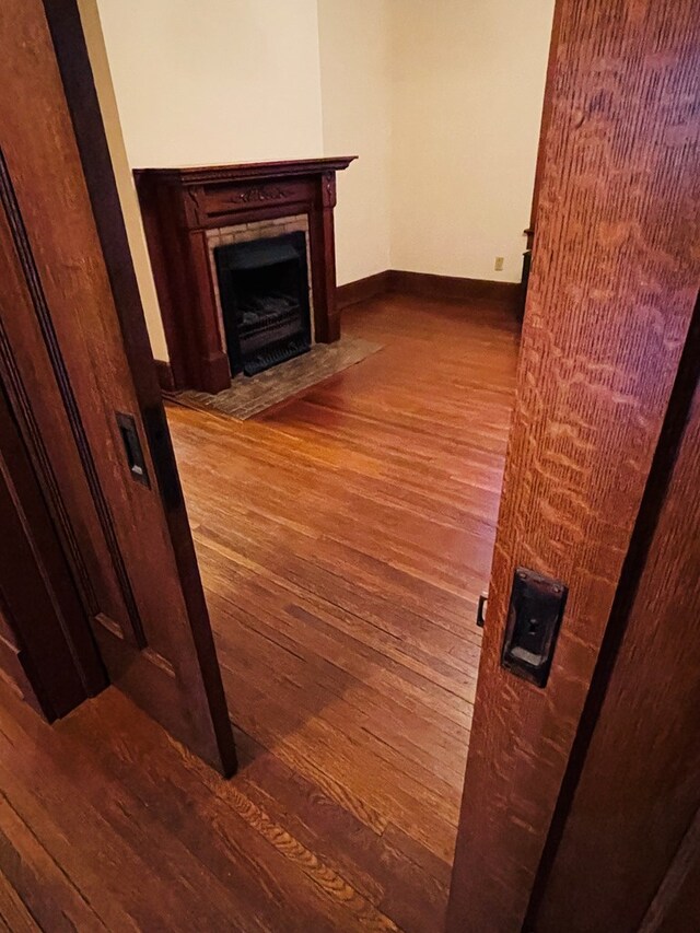 unfurnished living room featuring wood-type flooring, baseboards, and a fireplace